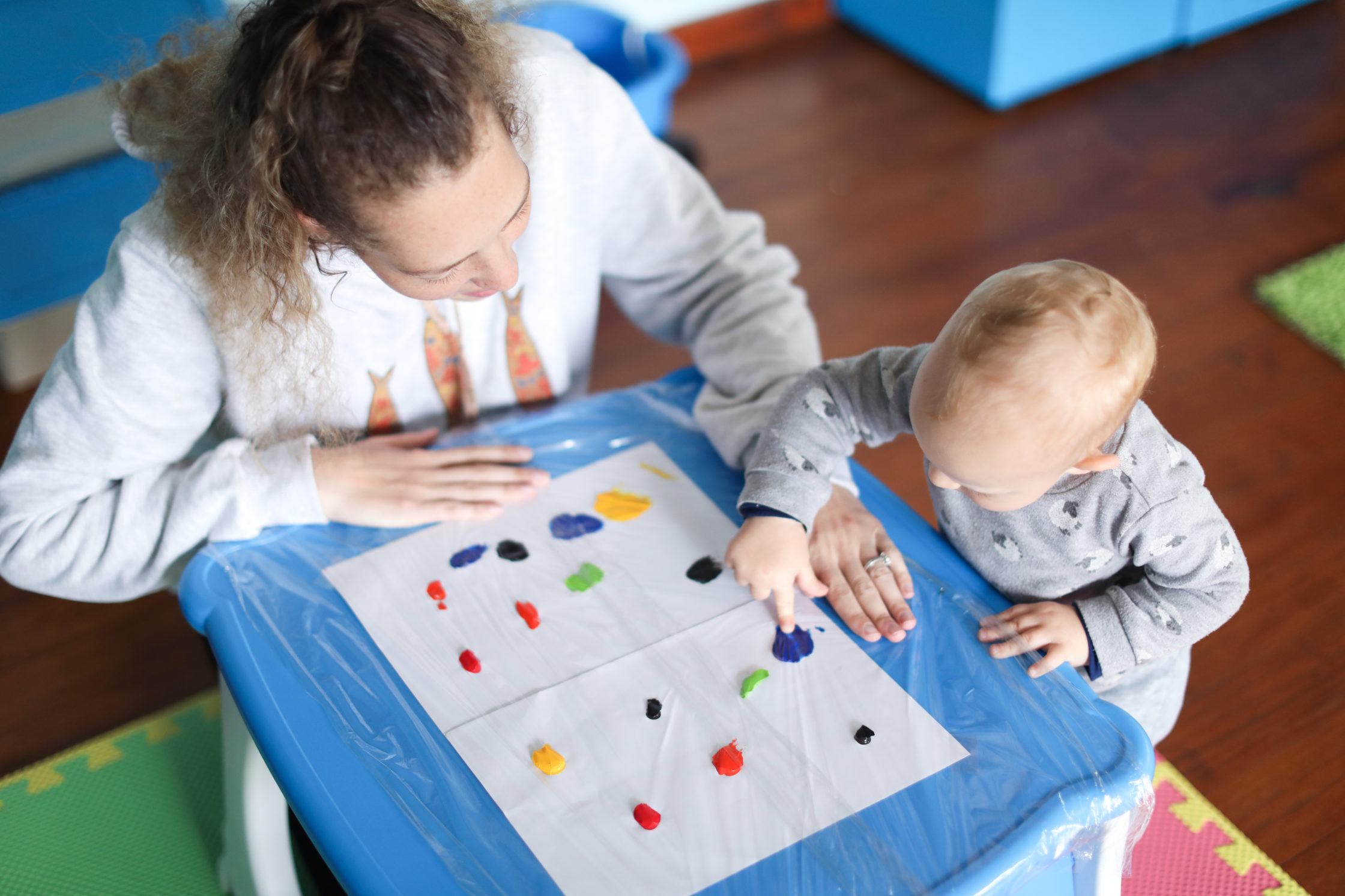 a Baby boy finger painting with his mother.