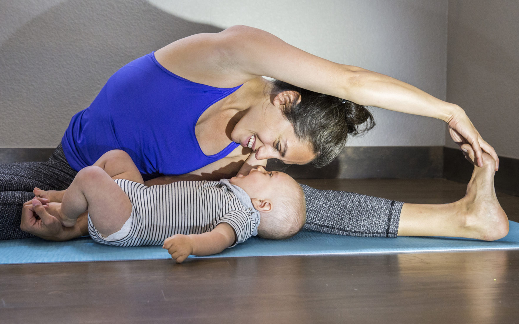 Happy mother stretches while admiring her baby boy